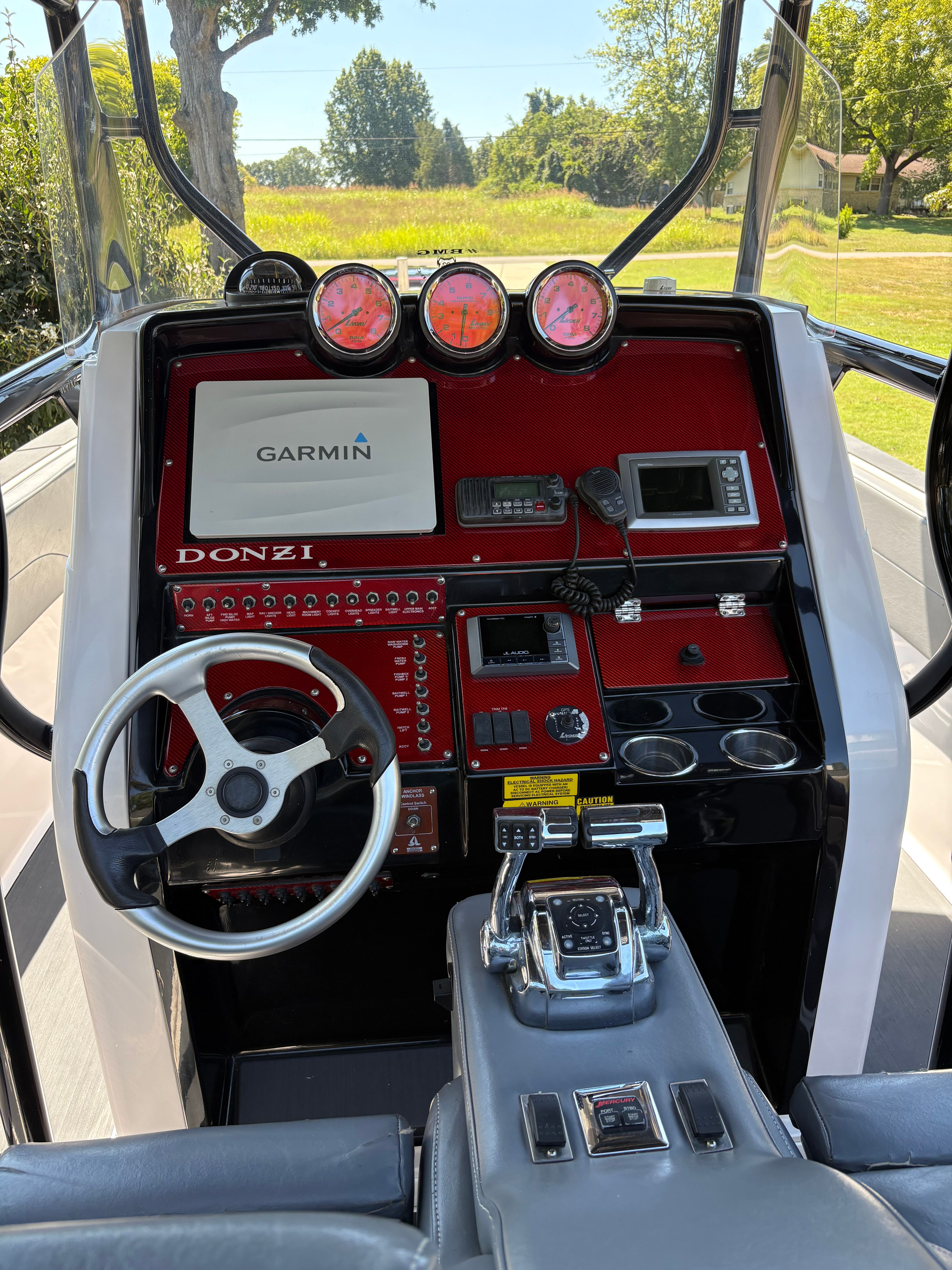 Donzi helm station with Garmin display, red carbon fiber dash, analog gauges, and VHF radio
