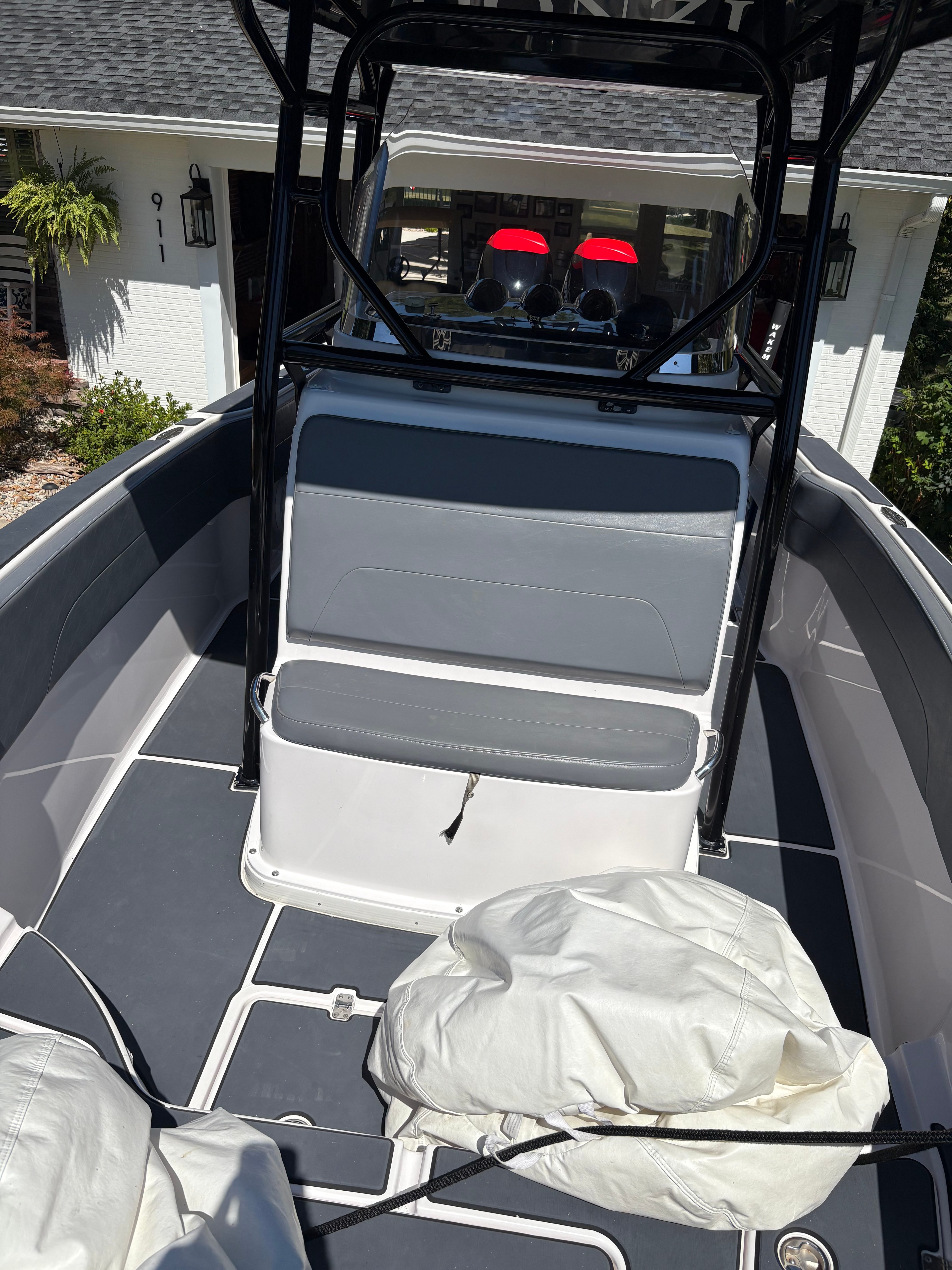 Mid-cabin view showing fold-down helm seat, forward seating, and T-top frame